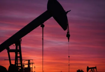 oil pumps silhouette against a vivid sunset, symbolizing the volatile world of transboundary oil resource management.
